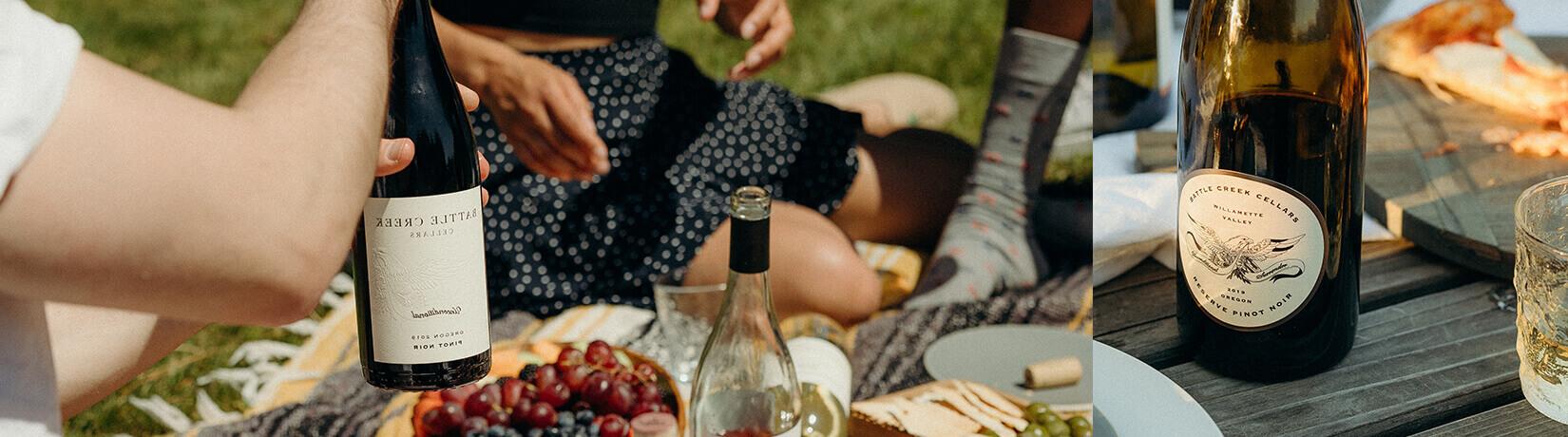 close up of people sharing wine and food around a picinic table